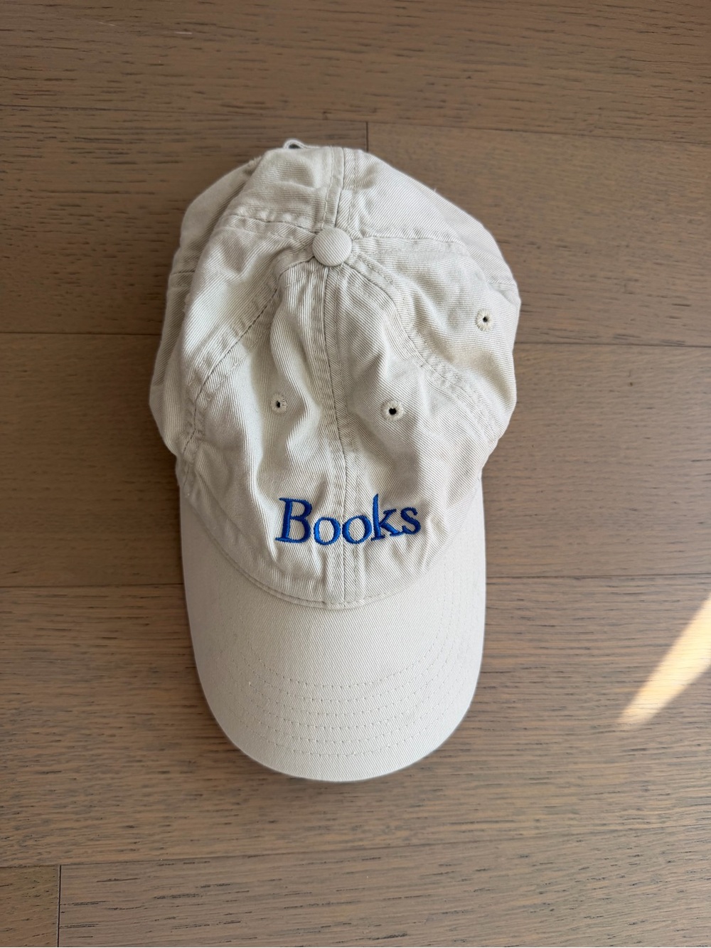 Cream baseball cap dad hat with blue embroidered 'Books' text